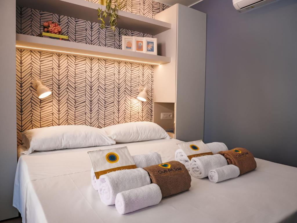 a bedroom with a white bed with towels on it at Club del Sole Rimini Family Resort in Rimini