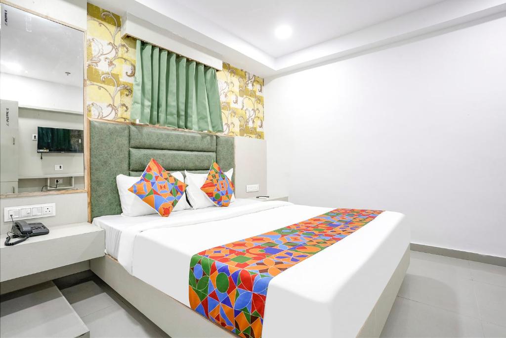 een witte slaapkamer met een bed met kleurrijke kussens bij FabHotel Grey Sky in Gandhinagar