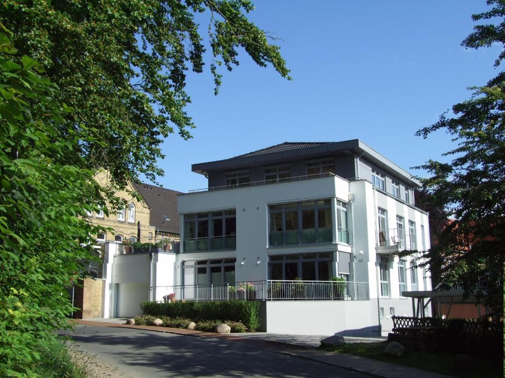 biały budynek z czarnym dachem w obiekcie fewo1846 - Penthouse Museumsberg - zwei Schlafzimmer und 2 Bäder mit Dachterrasse w mieście Flensburg