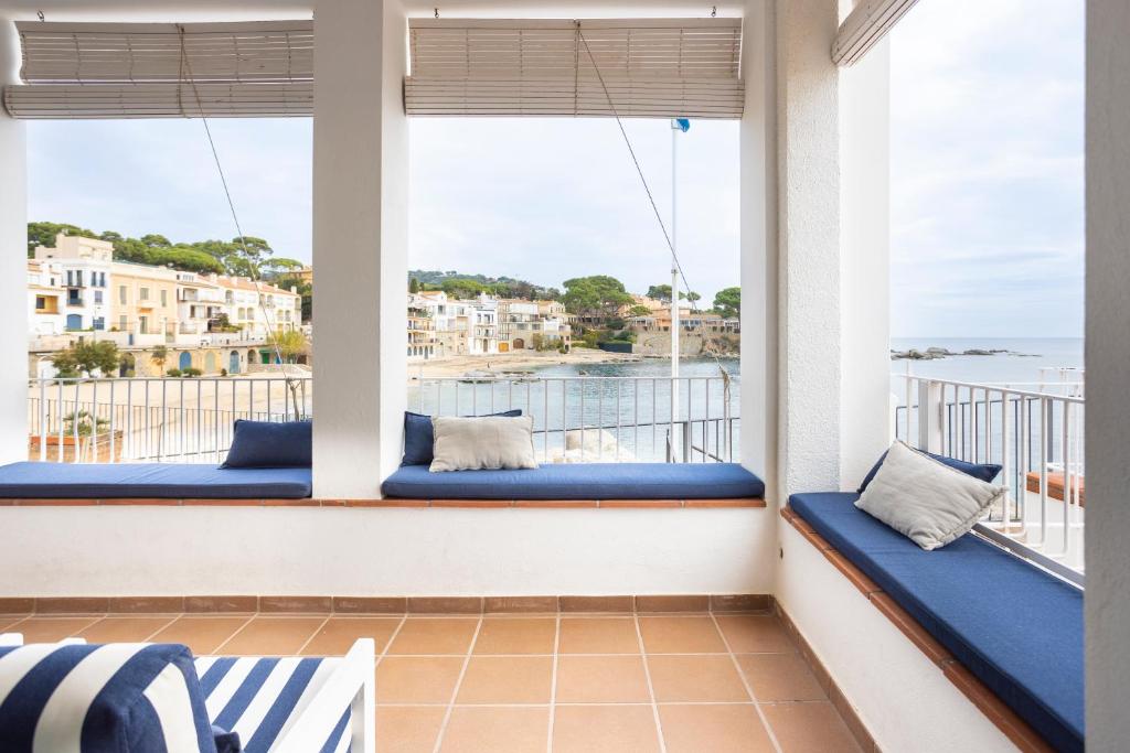 a balcony with blue cushions and a view of the ocean at CASA SOL I PLATJA Calella Palafrugell con Parking in Calella de Palafrugell