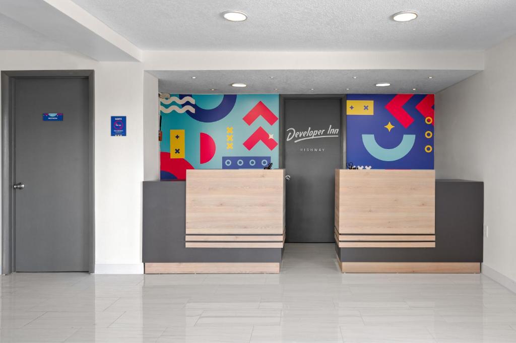 a lobby with two elevators and a wall with a sign at Developer Inn Highway, A Howard Johnson by Wyndham in Kissimmee