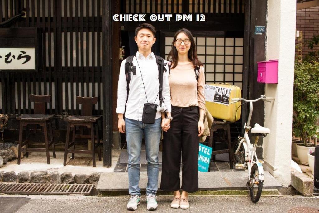 Un uomo e una donna in piedi davanti a un palazzo di Hostel Nakamura Kobe a Kobe