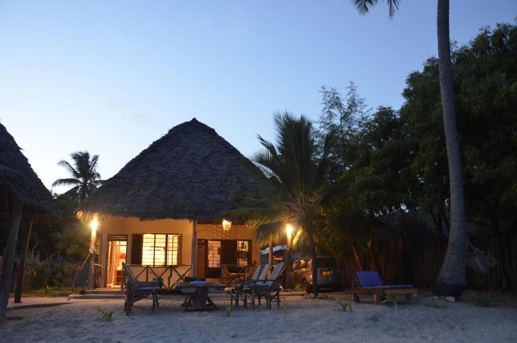 a house on the beach with chairs and palm trees at Lui Ushongo Beach House in Pangani
