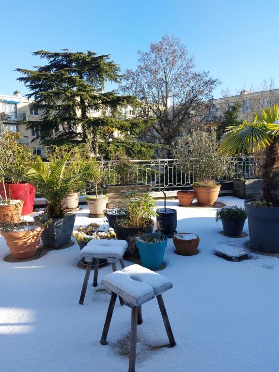 a snow covered patio with benches and potted plants at Chambre avec mezzanine dans une maison d'artiste in Rueil-Malmaison