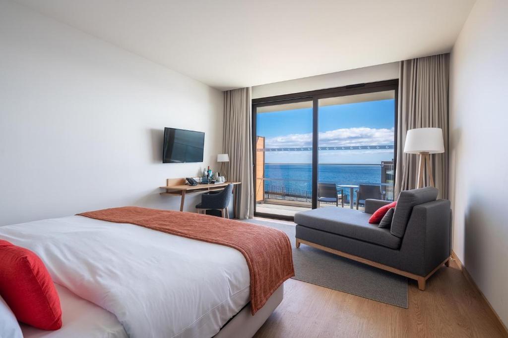 a bedroom with a bed and a chair and a window at Sentido Galomar - Adults Only in Caniço