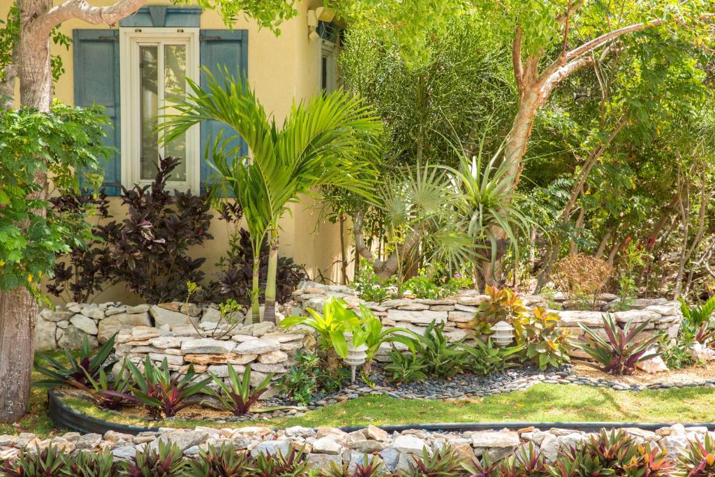 un jardín frente a una casa con una pared de piedra en Kokomo Botanical Resort - Caribbean Family Cottages, en Turtle Cove