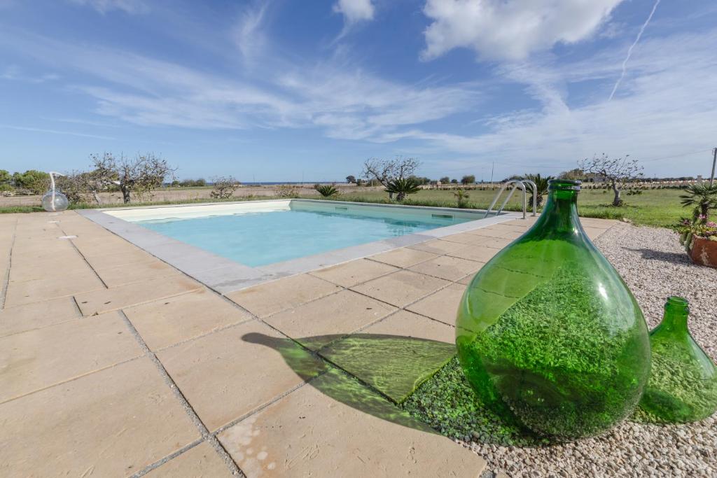 two green glass vases sitting next to a swimming pool at Villa Torre Guaceto by Typney in Carovigno