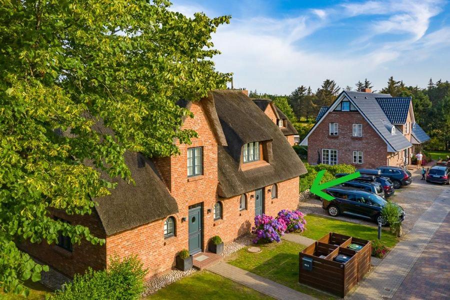 una grande casa in mattoni con auto parcheggiate in un parcheggio di Haus am alten Golfplatz a Wyk auf Föhr