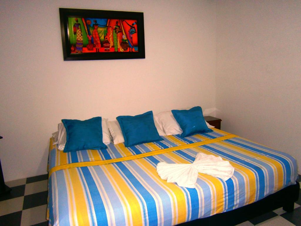 a bed with blue pillows and a painting on the wall at Hotel Shalom PHE Guaduas in Guaduas