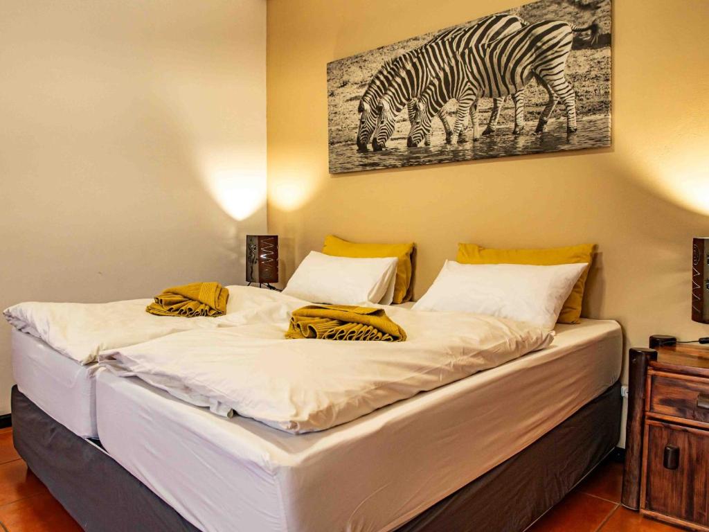 1 dormitorio con 1 cama con una foto de cebra en Bushbabies-Inn Self-Catering Accommodation, en Swakopmund