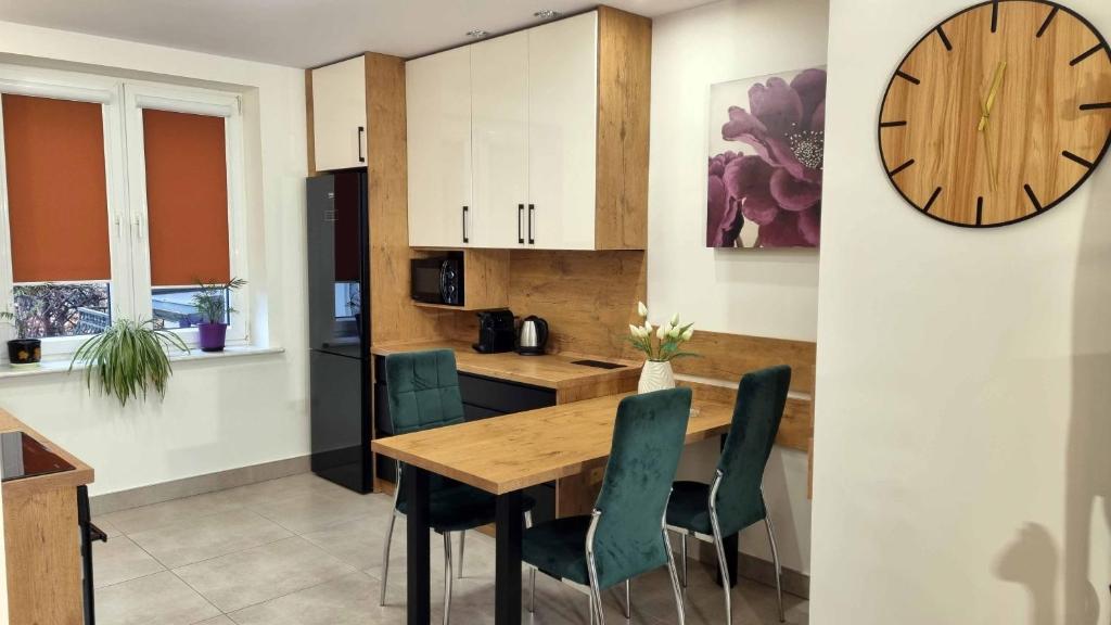 a kitchen with a wooden table and chairs and a clock at Apartament Renii in Tomaszów Mazowiecki