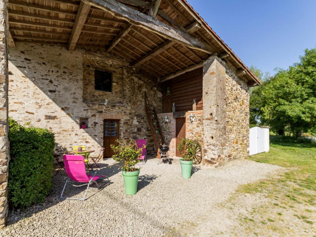 un patio avec des chaises roses et un bâtiment en pierre dans l'établissement Gîte Le Landreau, 3 pièces, 4 personnes - FR-1-306-804, à Le Landreau