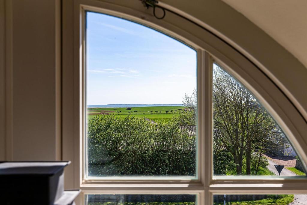 an arched window with a view of a field at Haus Amrumblick in Hedehusum