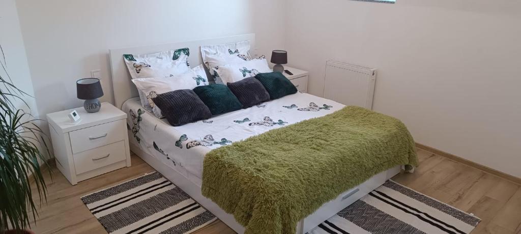 a bedroom with a bed with a green blanket and pillows at Moonlight Apartments Sibiu in Sibiu