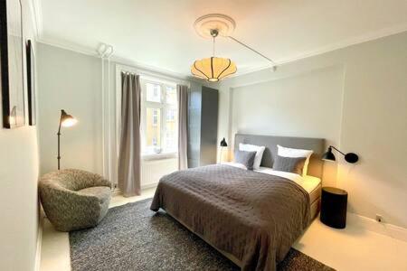 1 dormitorio con 1 cama, 1 silla y 1 ventana en Flat in Trendy and Vibrant Nørrebro Area, en Copenhague