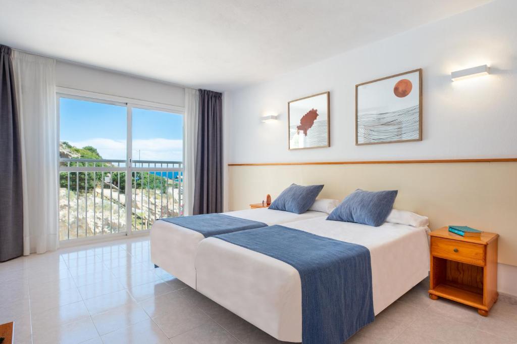 ein Schlafzimmer mit einem Bett und einem großen Fenster in der Unterkunft Apartamentos Vibra Tropical Garden in Ibiza-Stadt