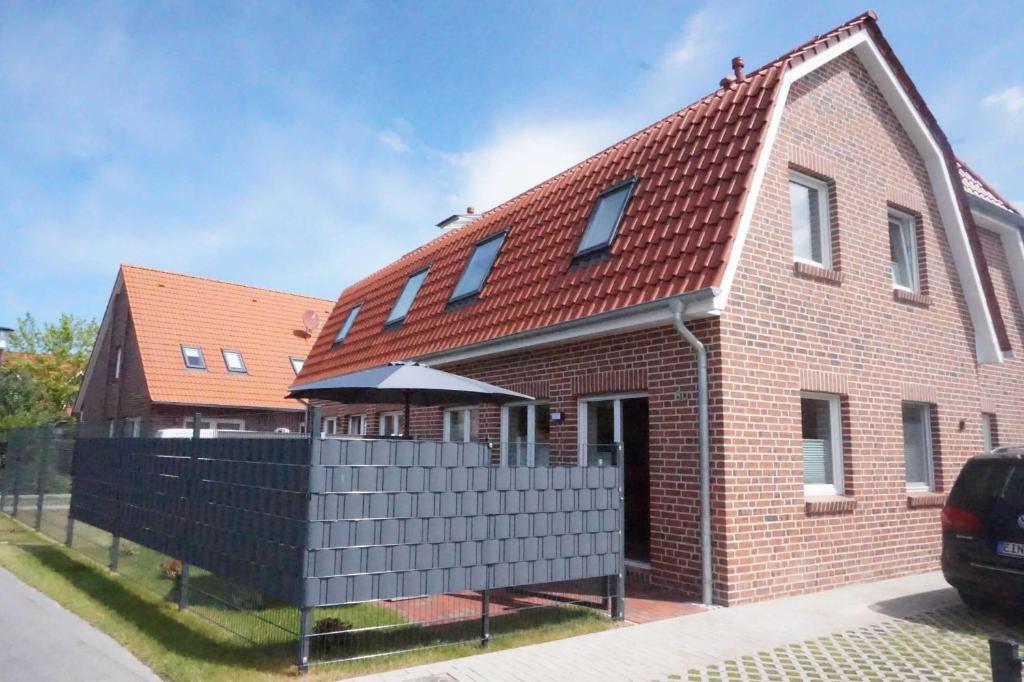 una casa de ladrillo rojo con techo rojo en Doppelhaushälfte Nordseewind, en Carolinensiel