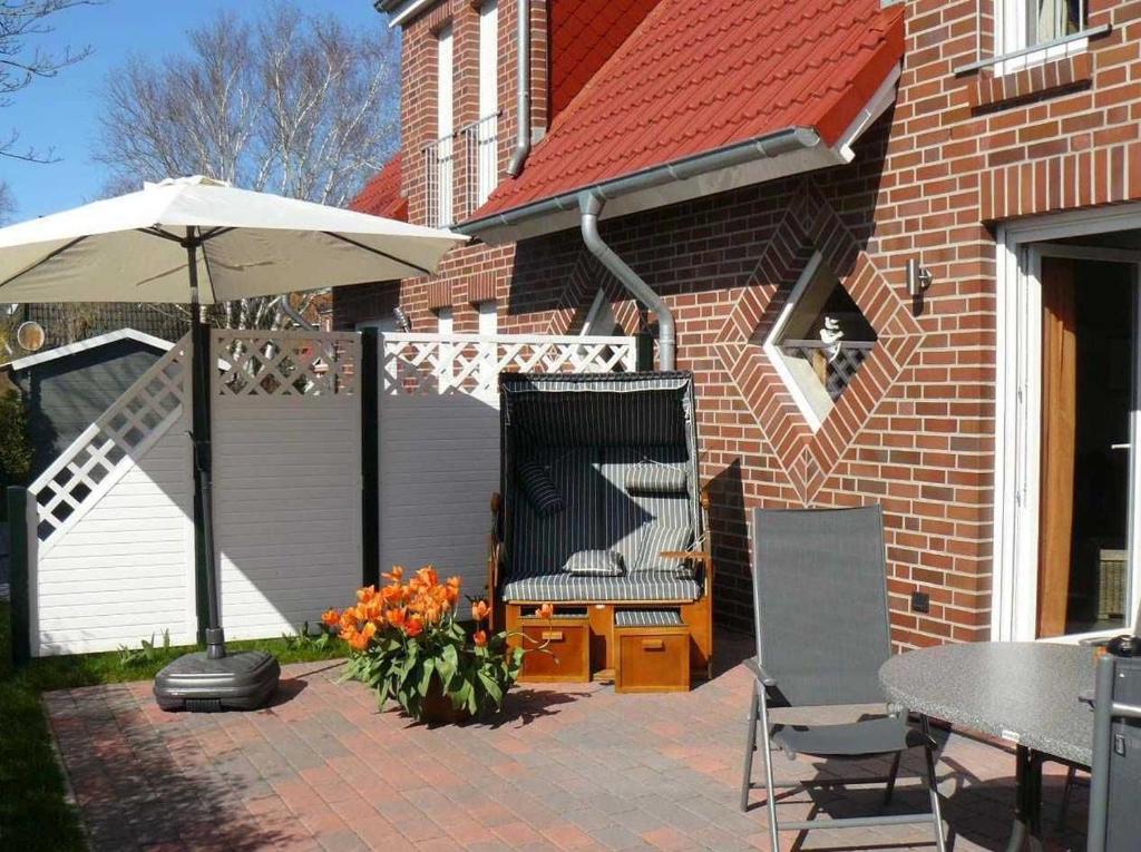 une terrasse avec un parasol, une table et des chaises dans l'établissement Ferienhaus Ambiente, à Harlesiel