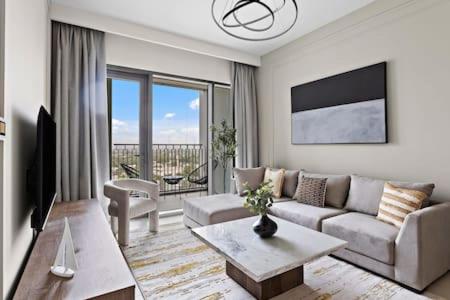 een woonkamer met een bank en een tafel bij Silkhaus luxurious 1BDR in new tower with pool & gym in Dubai