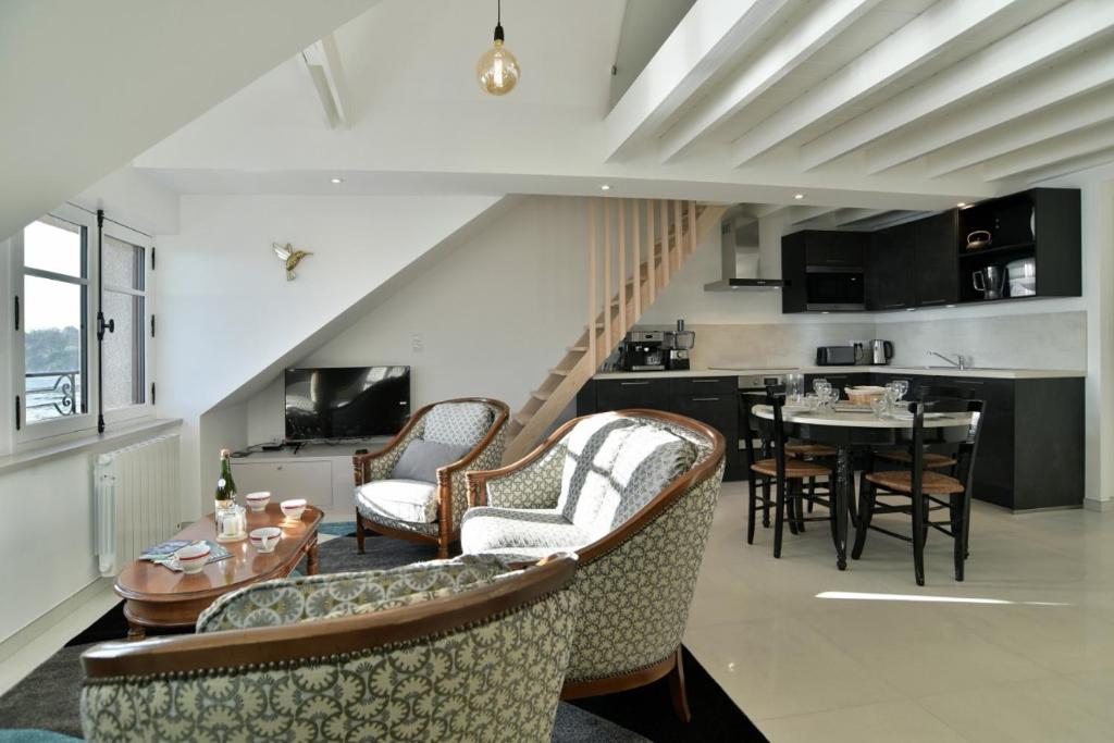 un soggiorno con sedie e tavolo e una cucina di LOstra 2 - Appartement avec mezzanine a Cancale