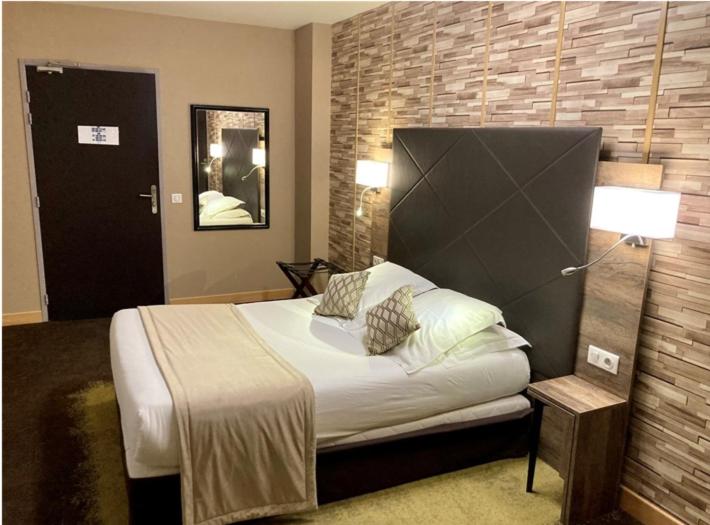 a bedroom with a bed and a brick wall at Logis Hôtel & Restaurant - Le Mouton Blanc in Cambrai