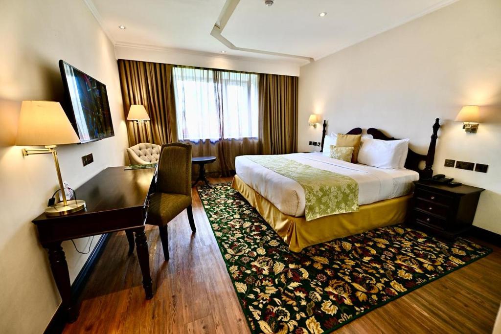 ナクルにあるMidland Hotel Nakuruのベッドとデスクが備わるホテルルームです。