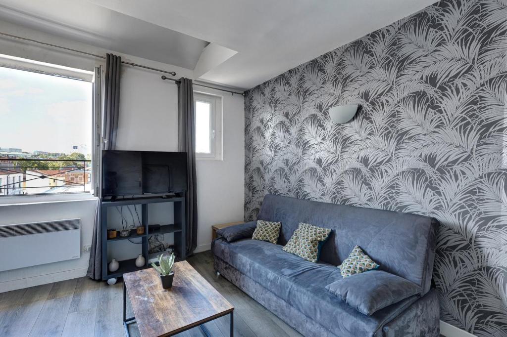 - un salon avec un canapé bleu et un mur dans l'établissement 804 Suite Styling - Superbe Duplex, à Bagnolet