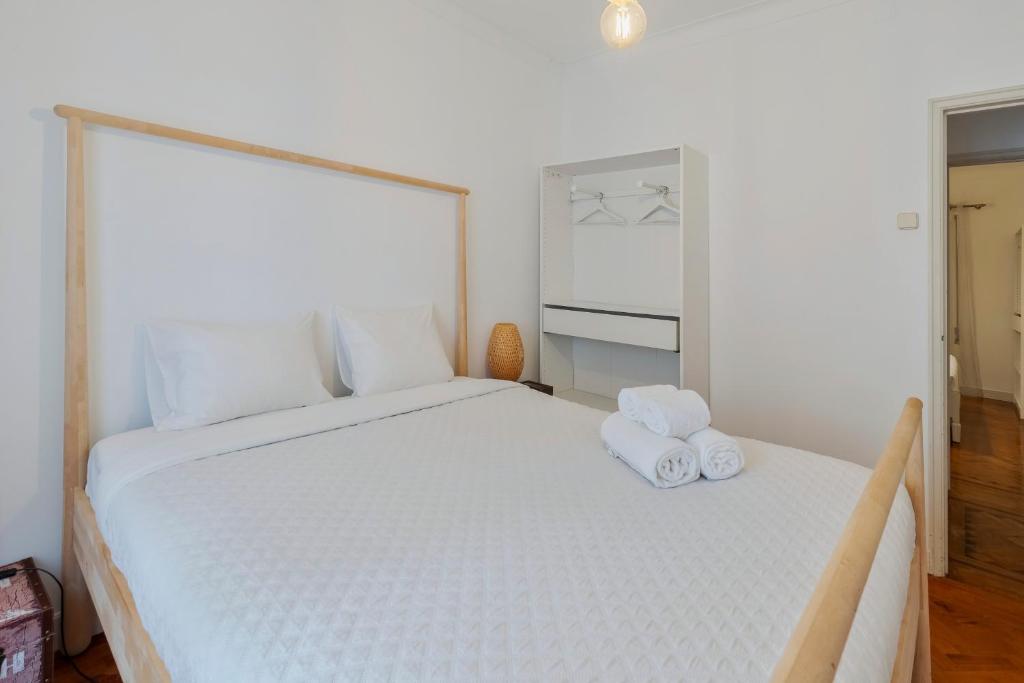 a bedroom with a large white bed with towels on it at Pátios das Marias - Rosas in Setúbal