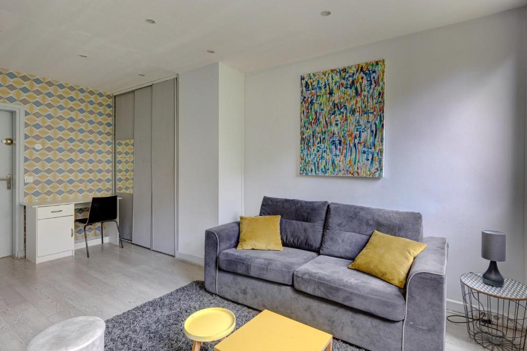 a living room with a couch and a painting on the wall at 235 Home Madrid Concept in Paris