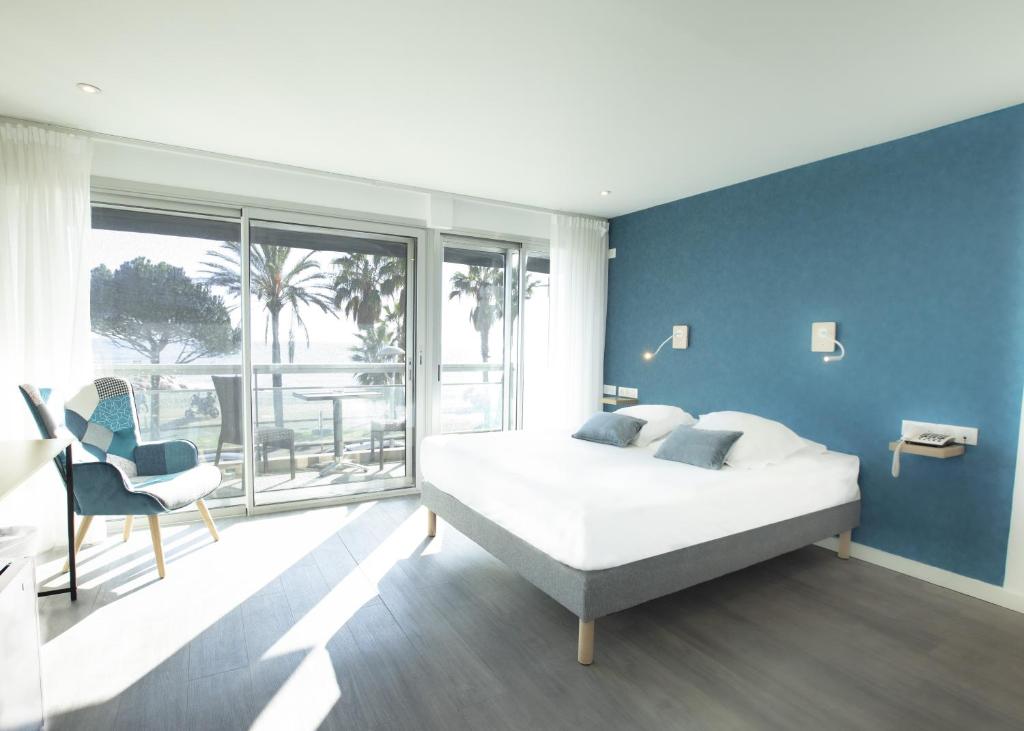 a bedroom with a white bed and a blue wall at Tiercé Hotel in Cagnes-sur-Mer