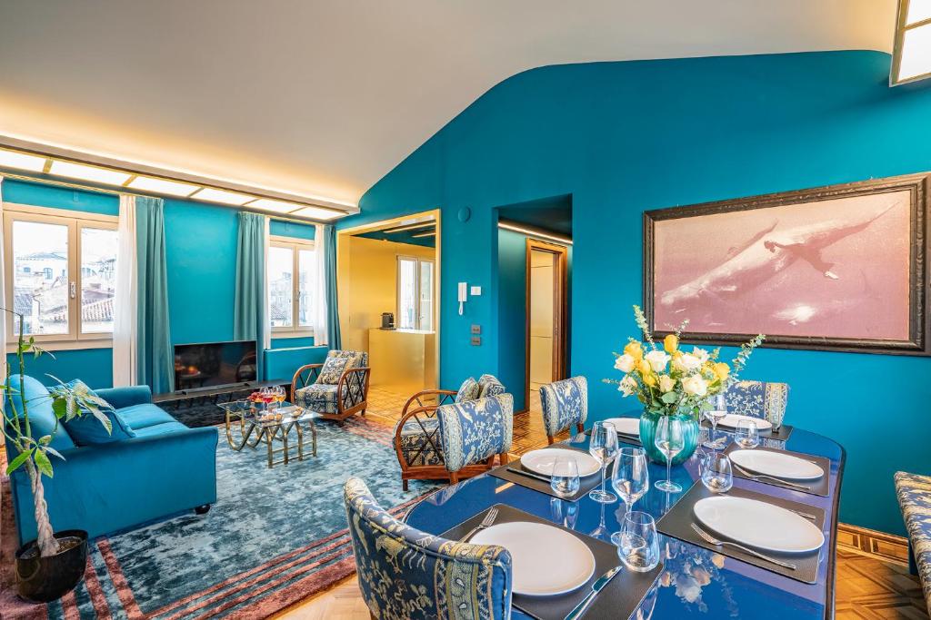 una sala de estar azul con mesa y sillas en Dimora San Trovaso Enchanting Four-bedrooms, en Venecia
