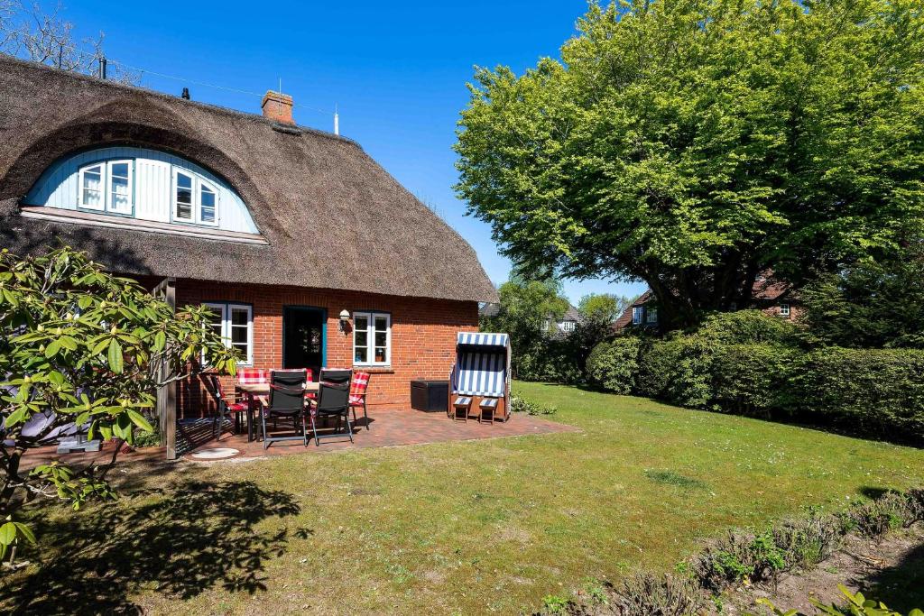 Cette maison au toit de chaume dispose de chaises et d'une terrasse. dans l'établissement Haus Strandruhe, à Wyk auf Föhr