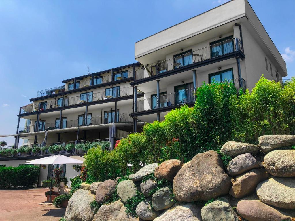 a building with a rock wall in front of it at AHG Riva Del Sole Hotel in Moniga