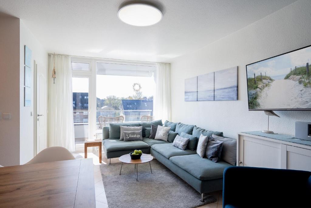 sala de estar con sofá azul y mesa en H3 53 - Hanseat - Außenschwimmbad, en Scharbeutz