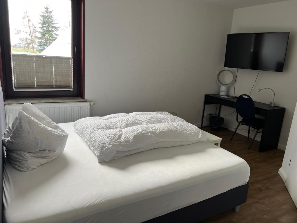 a bedroom with a white bed with a window and a television at Woltorfer Landkrug in Peine