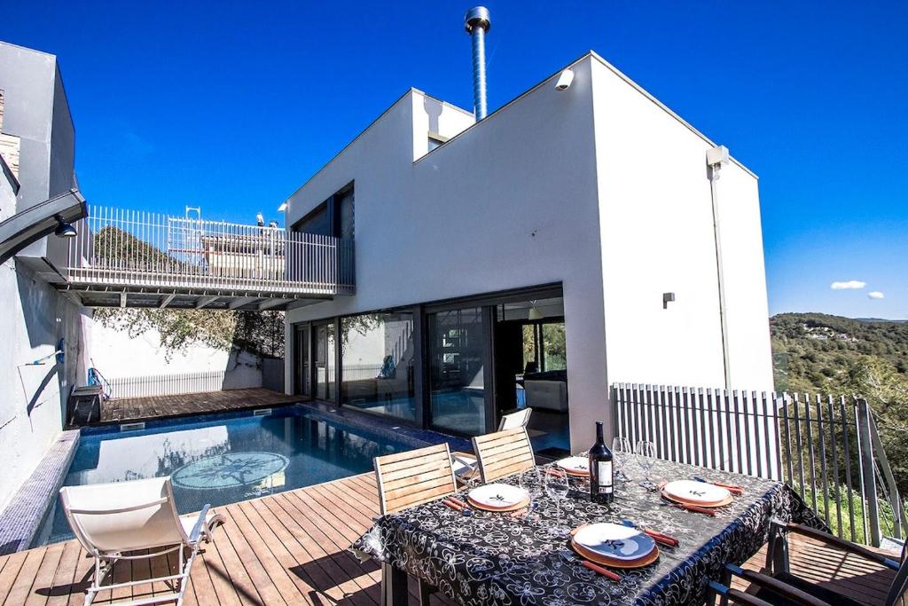 een huis met een tafel en stoelen en een zwembad bij Catalunya Casas Modern Hilltop Haven with private pool 7km to beach in Castellet