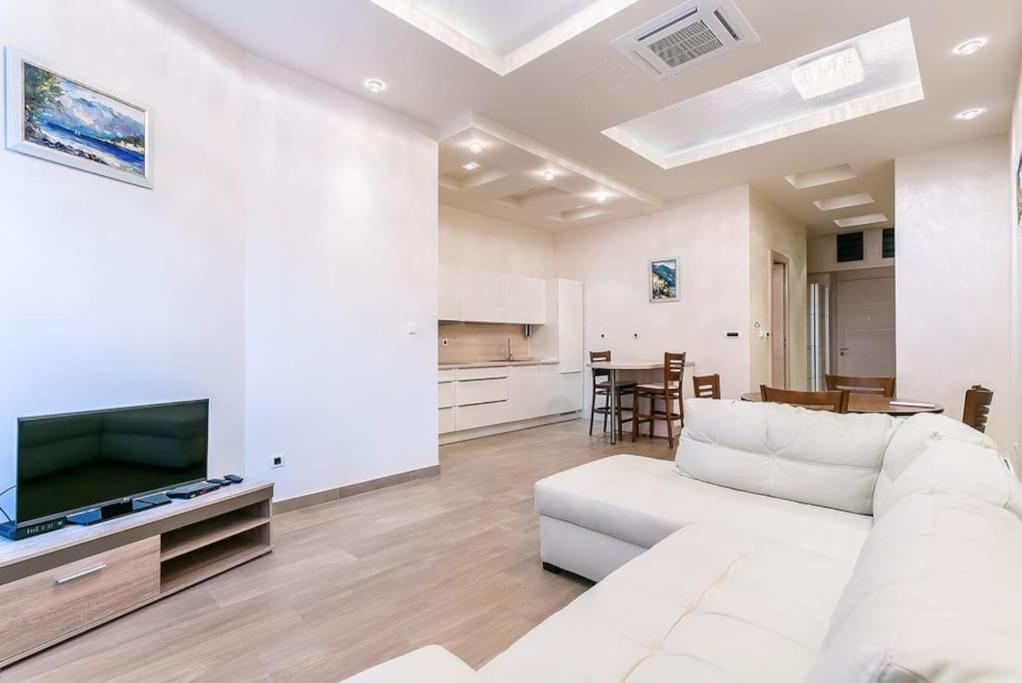 a white living room with a white couch and a tv at Stylish spacious apartment near the sea in Budva