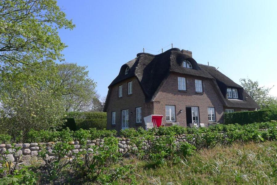 Alkersum的住宿－Haus Weitblick，田野上茅草屋顶的老房子