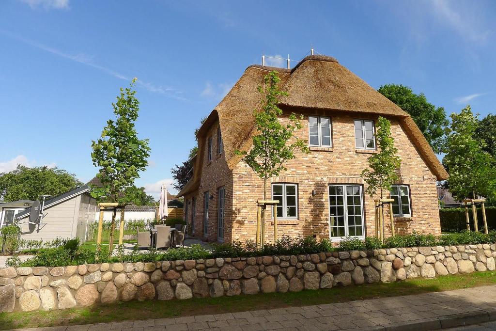 une vieille maison en briques avec un toit de chaume dans l'établissement Haus Windrose, à Wrixum