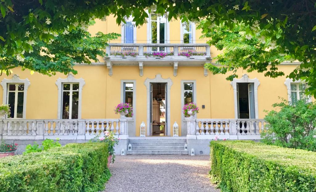 a yellow house with a balcony and bushes at Villa Verganti Veronesi in Inveruno