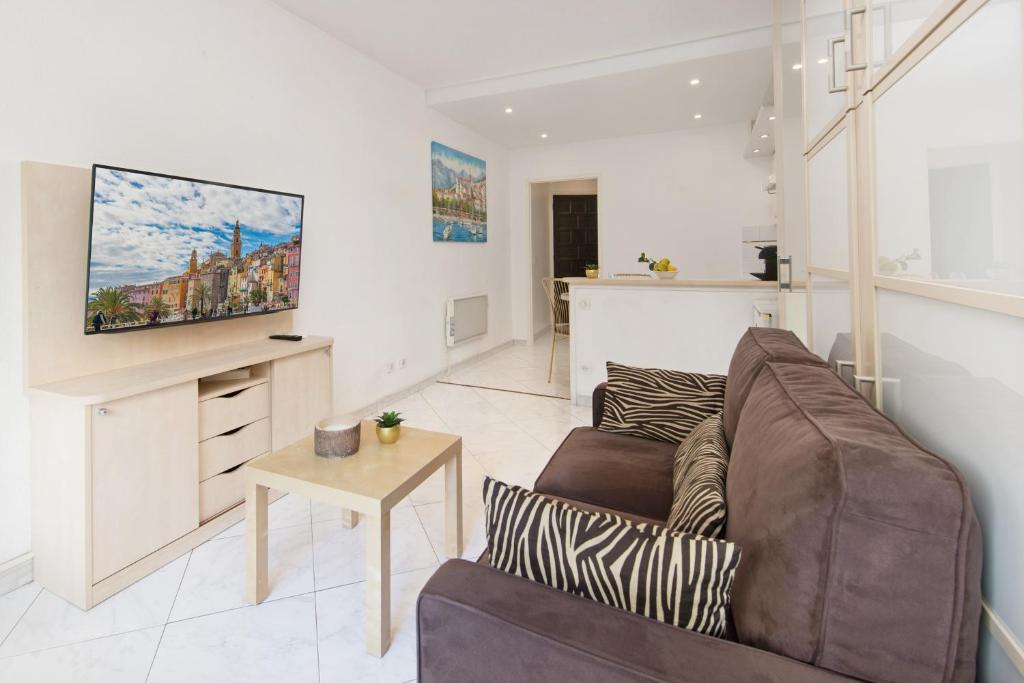 a living room with a couch and a tv on a wall at COSY STUDIO - Résidence front de mer - Menton in Menton