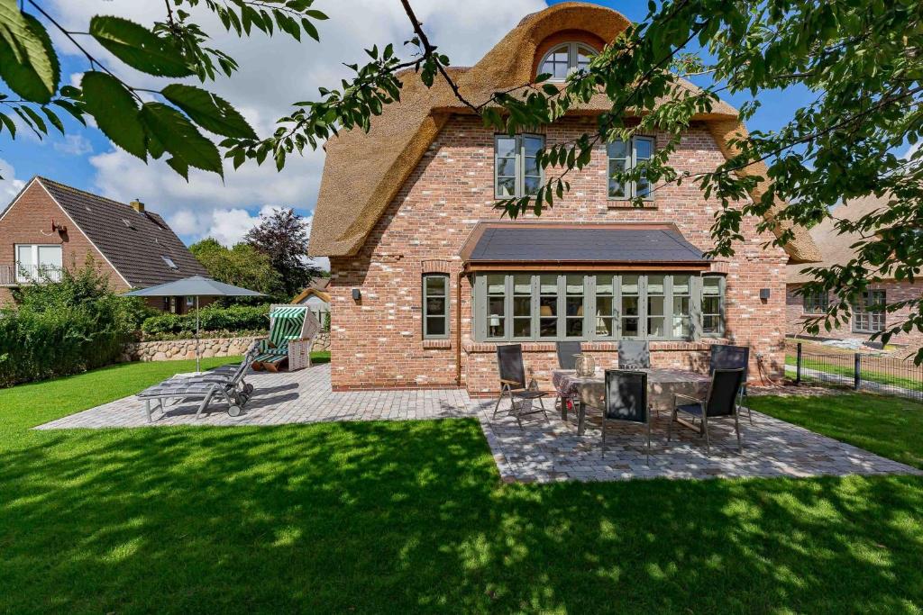 a brick house with chairs and a table in the yard at Hüs Holm in Alkersum