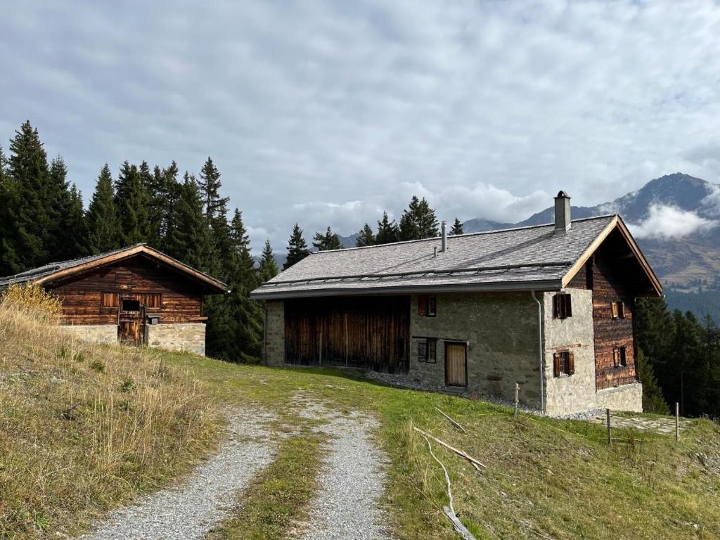 Alpine Hut Acla Sissi Lenzerheide for 10 people في فالبيلا: منزل قديم على تلة مع طريق ترابي