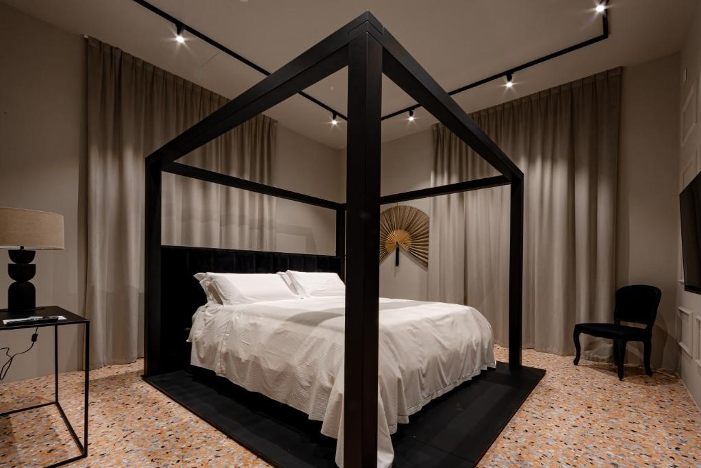 Exclusive Room Pescara في بيسكارا: غرفة نوم مع سرير مظلة سوداء مع ملاءات بيضاء