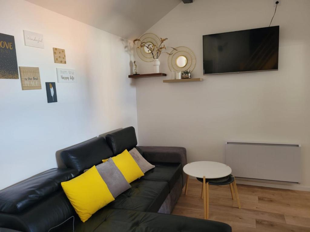 a living room with a black leather couch and a tv at Appartement COSY proche de Paris in Chambourcy