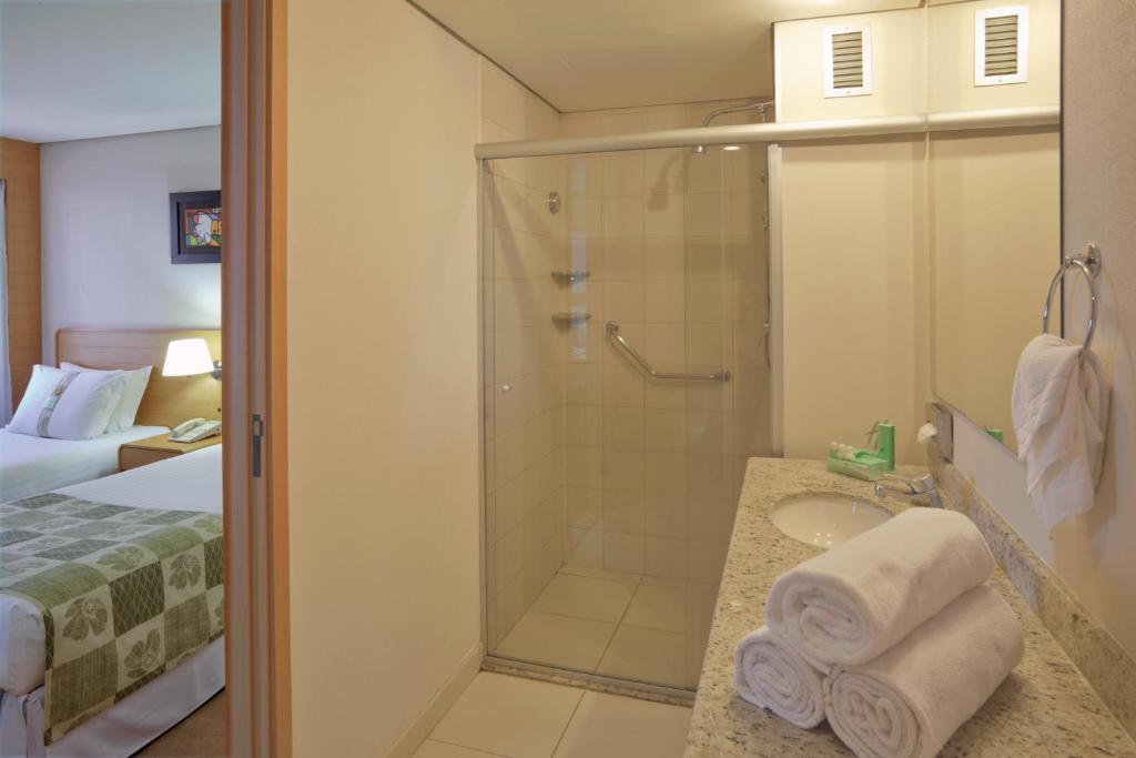 a bathroom with a shower and a bed and a sink at Holiday Inn Parque Anhembi, an IHG Hotel in São Paulo