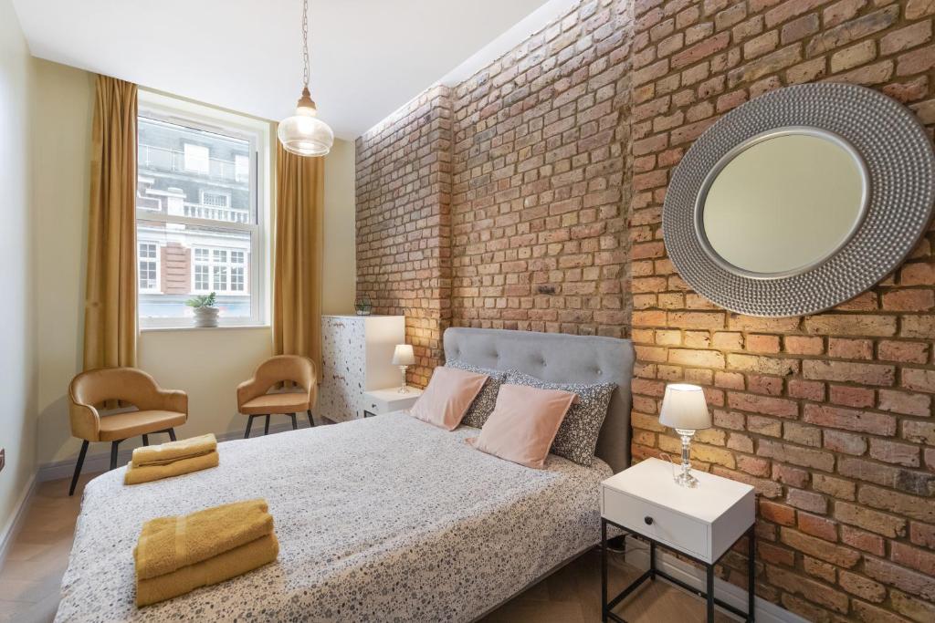 a bedroom with a brick wall and a bed with a mirror at Cozy Retreat Near Downtown with Parking in London