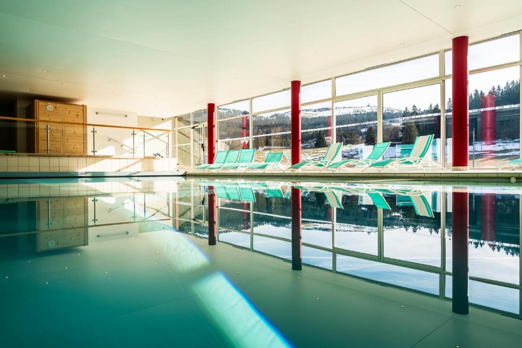 - une piscine avec des chaises dans un bâtiment dans l'établissement Hôtel-Club Côté Dole, USSIM Vacances Les Rousses, aux Rousses