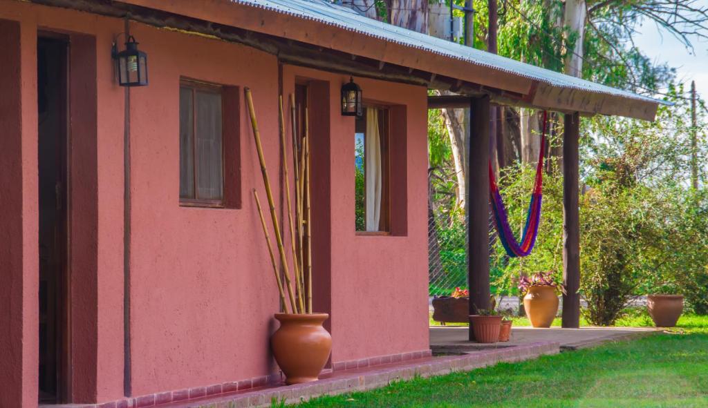 a pink house with potted plants on the porch at La Casona Cabañas in Villa Ciudad Parque