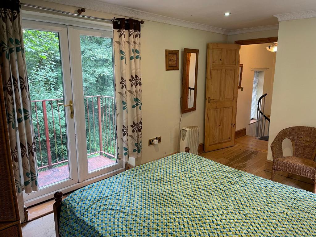 a bedroom with a bed and a balcony with windows at Llangollen cosy apartment in Llangollen